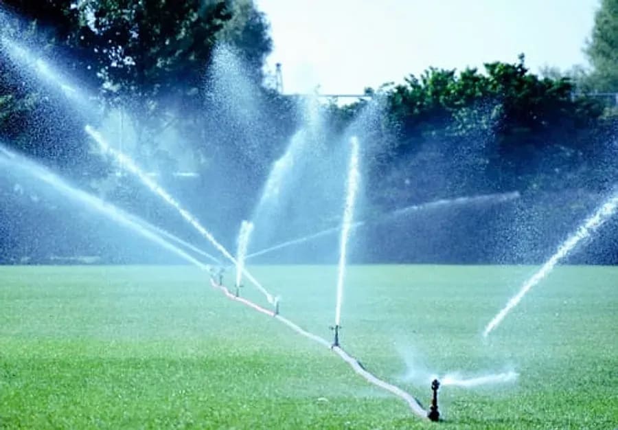 Sprinkler irrigation system running across a green lawn in Mesa, Arizona