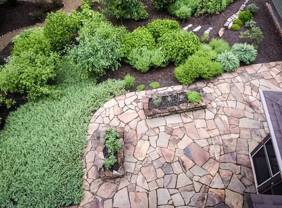 Natural stone travertine patio surface bordered by landscaping at an Arizona home